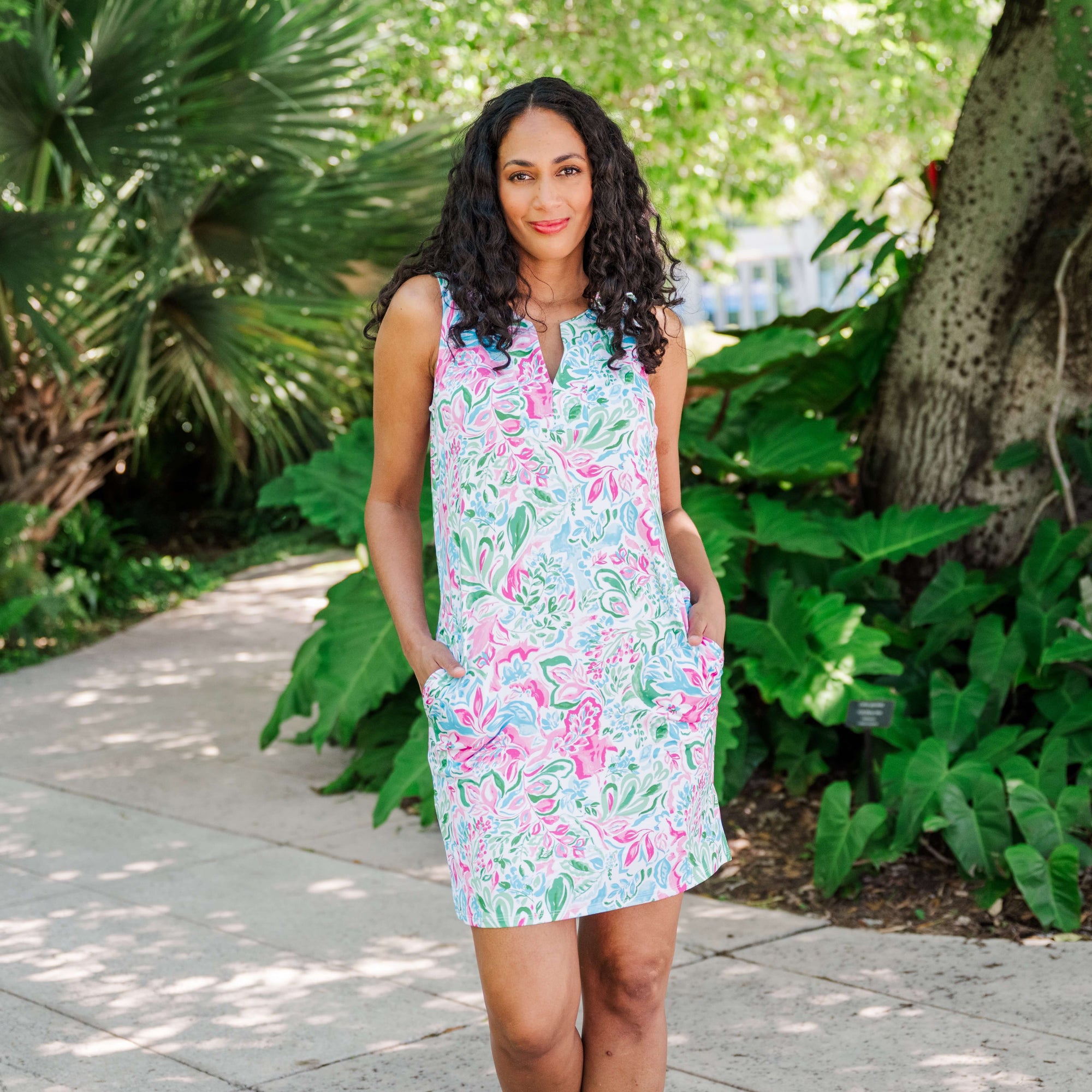 Woman wearing a colorful floral dress standing in a garden