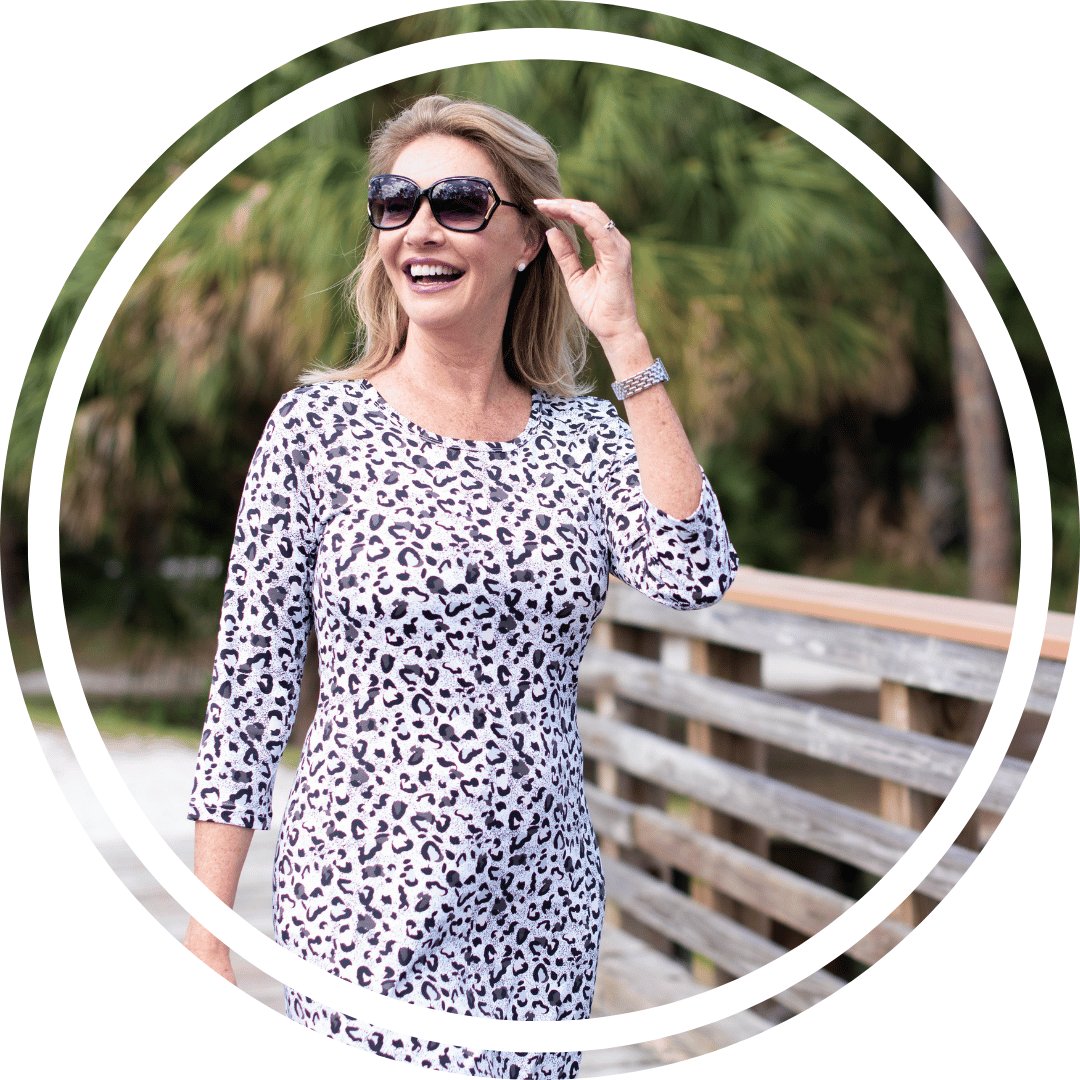 older woman posing by the water wearing resort wear