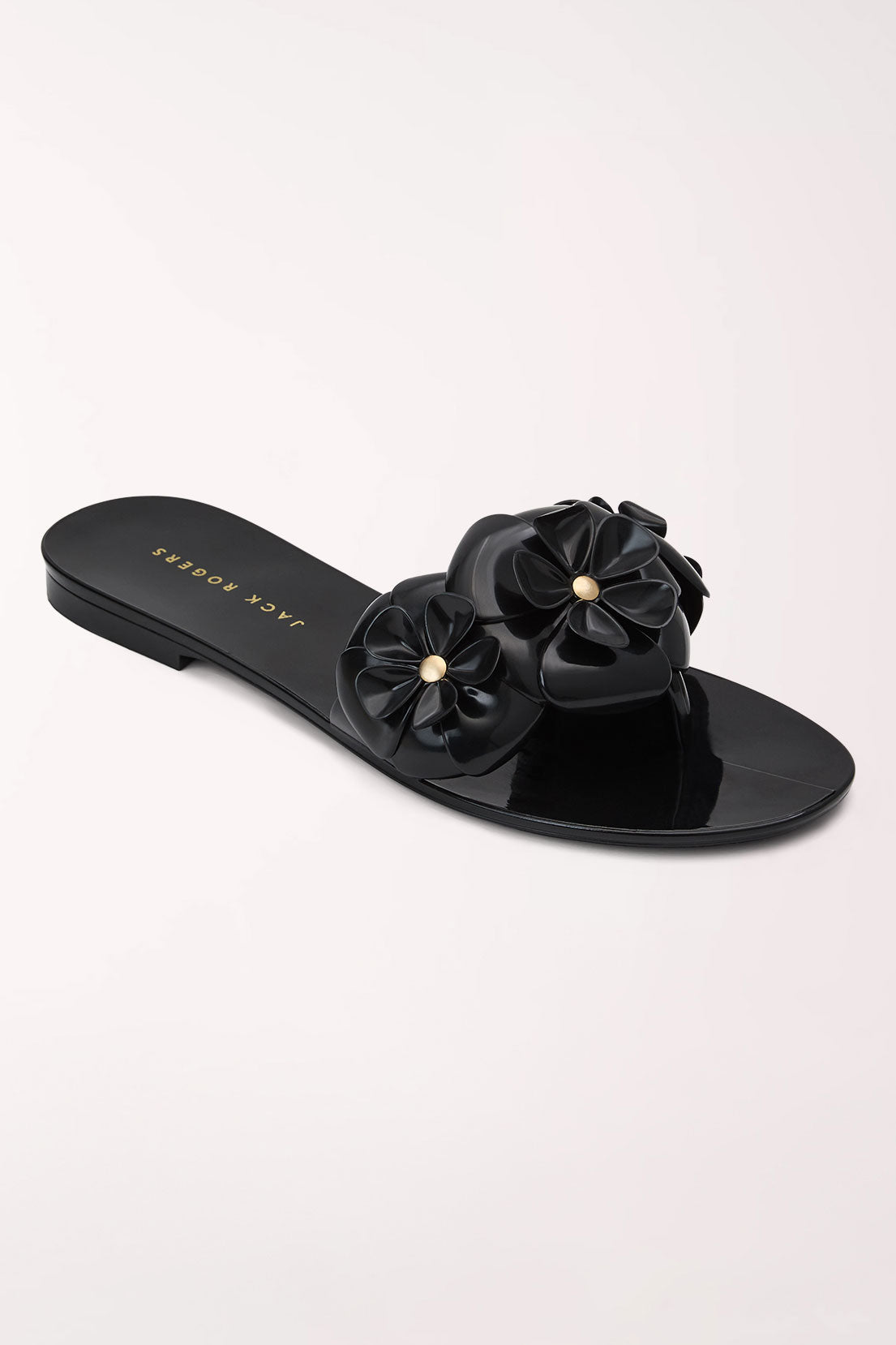 A black patent leather slide sandal by Jack & Jones, featuring three dimensional flower embellishments on the strap with small gold bead centers, shown on a light off-white background.