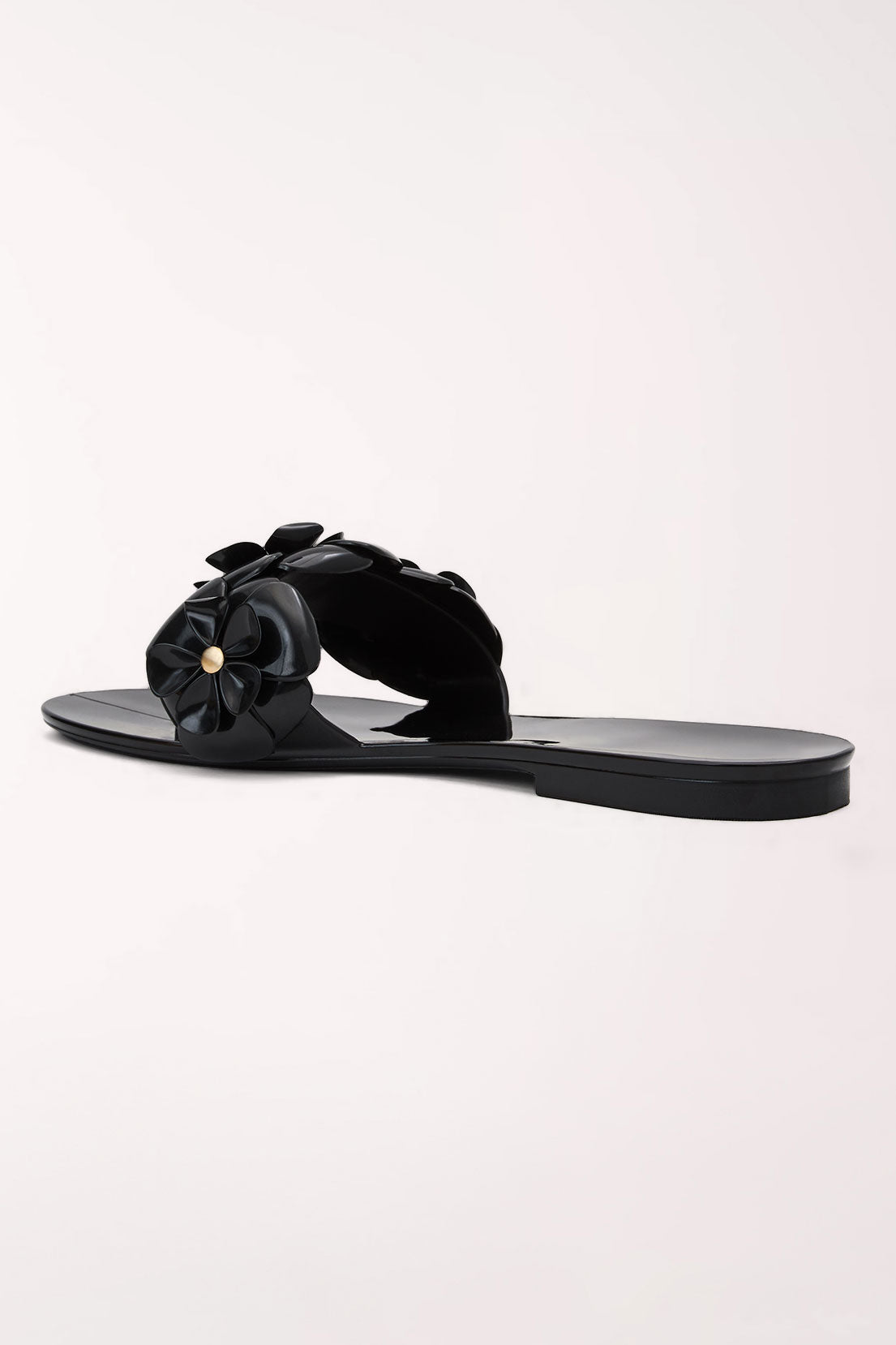 A pair of black patent jelly slide sandals by Jack Rogers, featuring large 3D floral embellishments across the straps with small gold-tone center details.