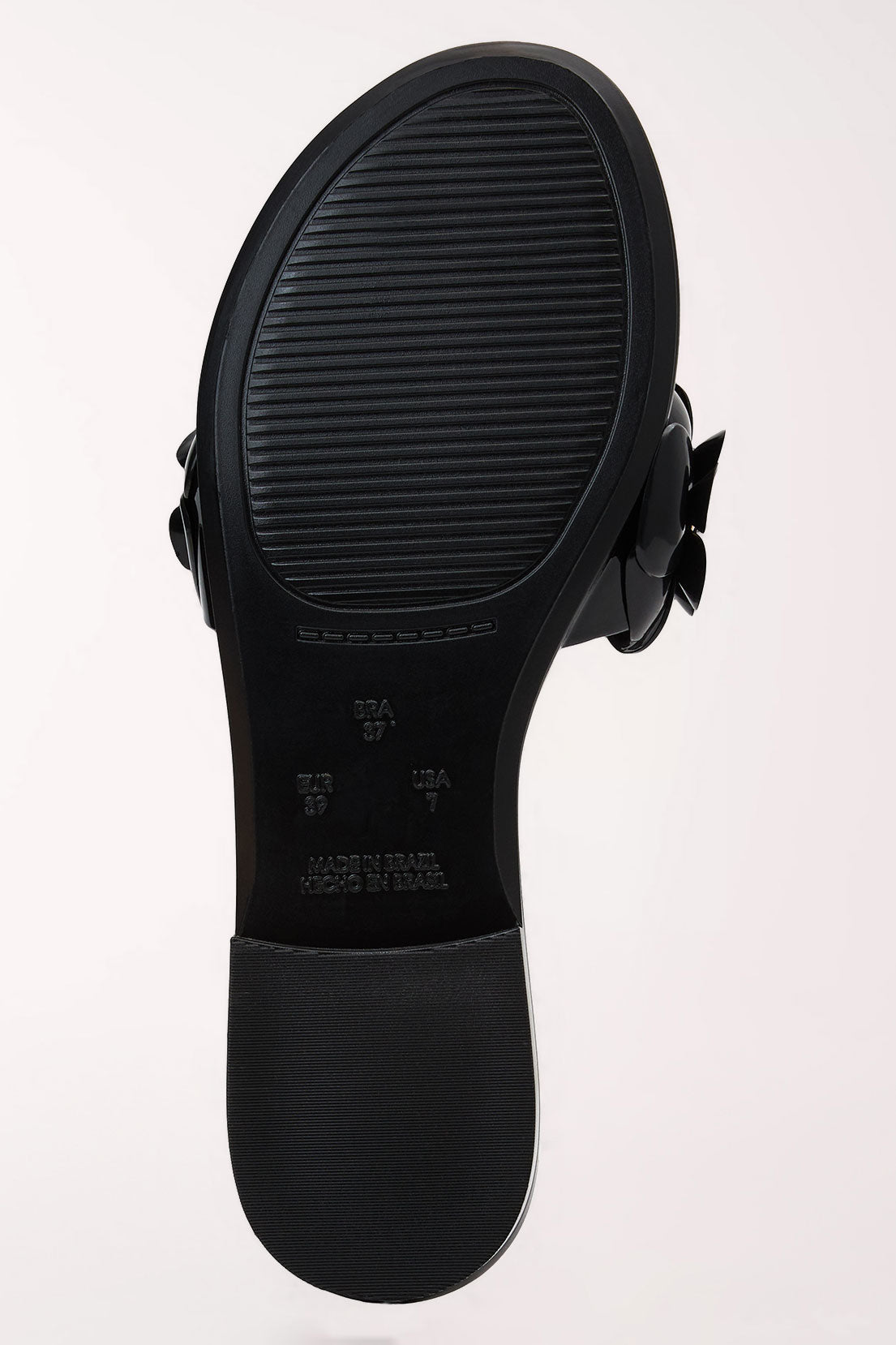 A pair of black patent jelly slide sandals by Jack Rogers, shown from underneath on a light off-white background.