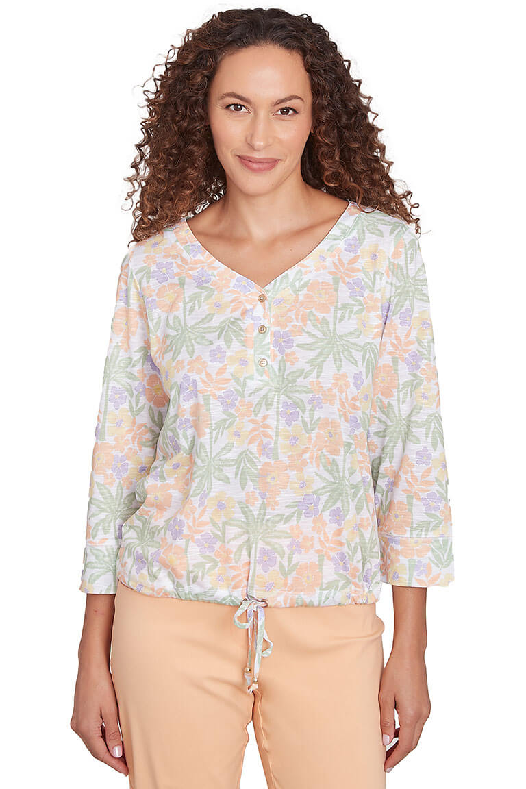 A front shot of a model wearing a floral henley top with 3/4 sleeves and a V-neck, in a mix of pink, white, and green colors.
