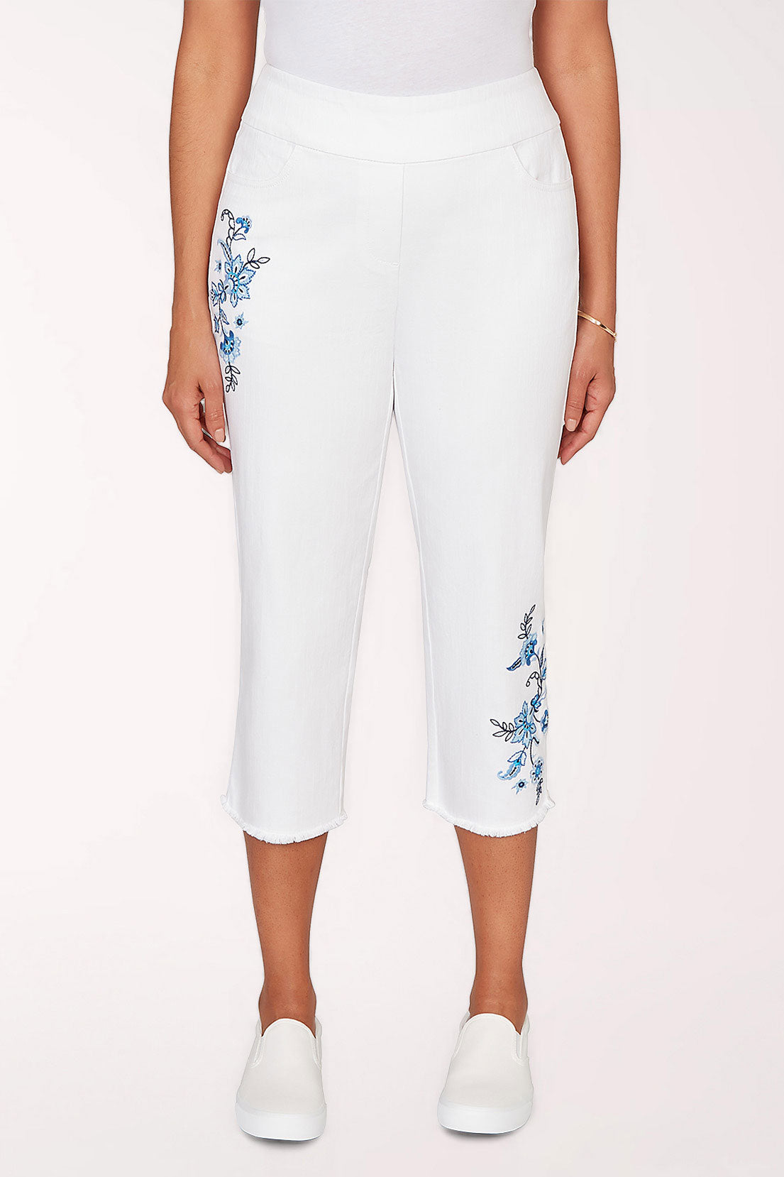 White capri pants with floral embroidery on a white background