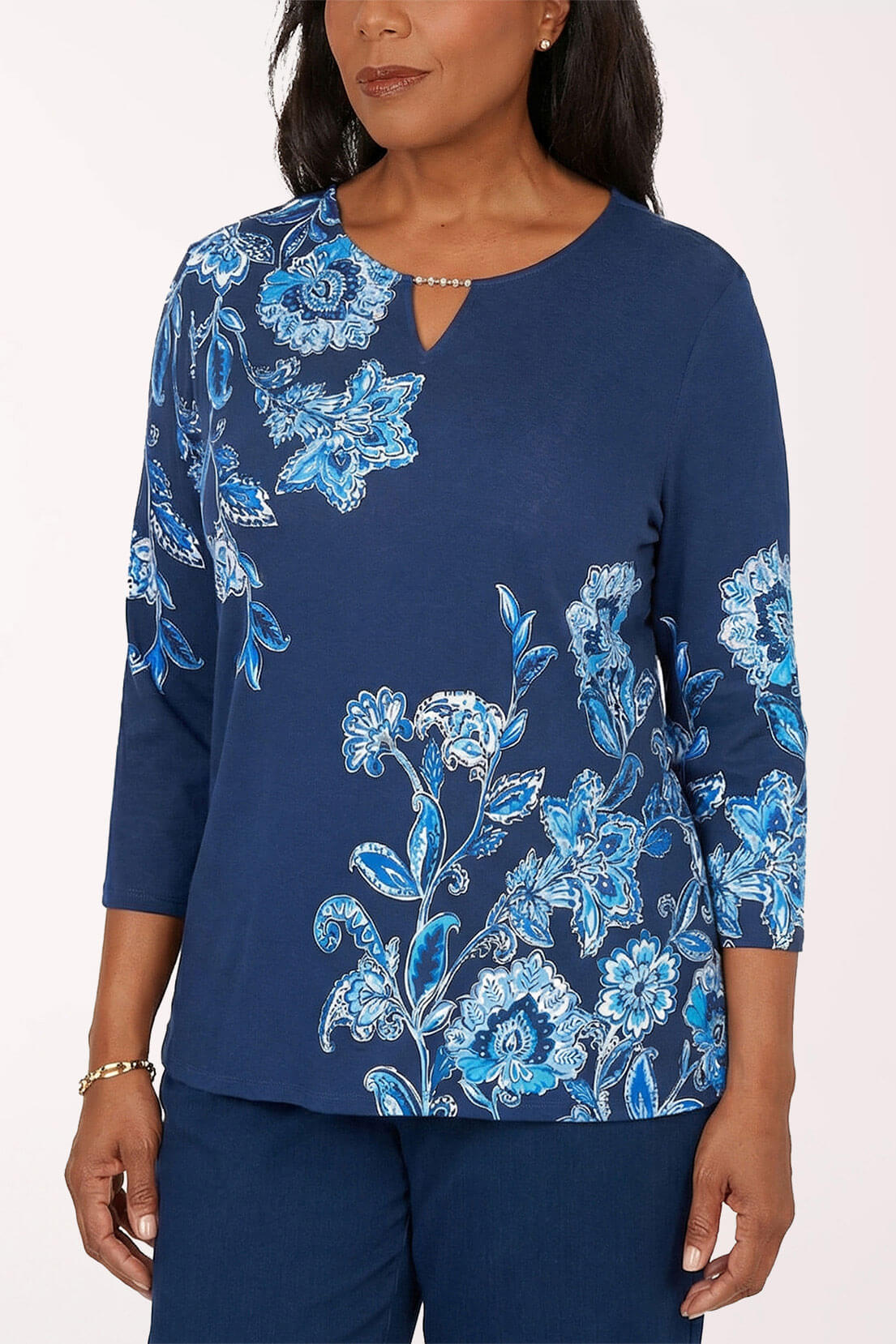Woman wearing a blue floral patterned top against a white background