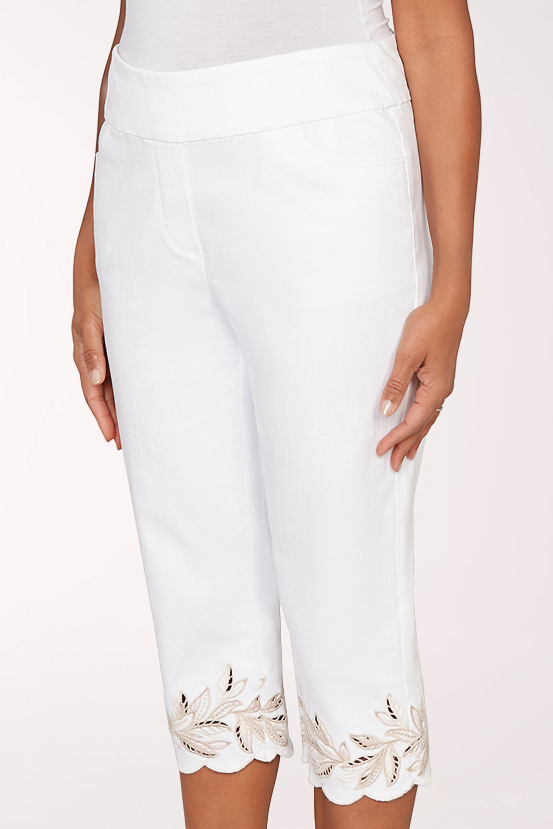 Person wearing white pants with lace trim and brown shoes on a white background
