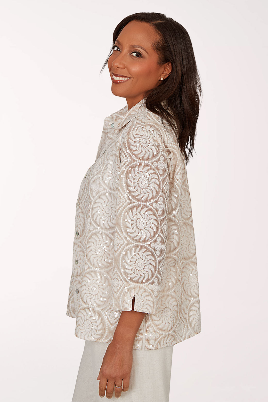 Woman wearing a patterned beige jacket over a white shirt on a white background