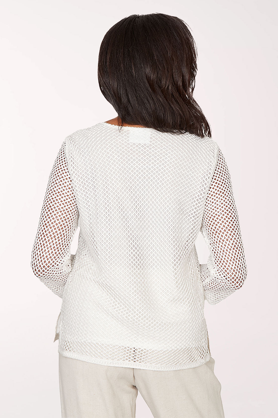 Woman wearing a white mesh top against a plain background