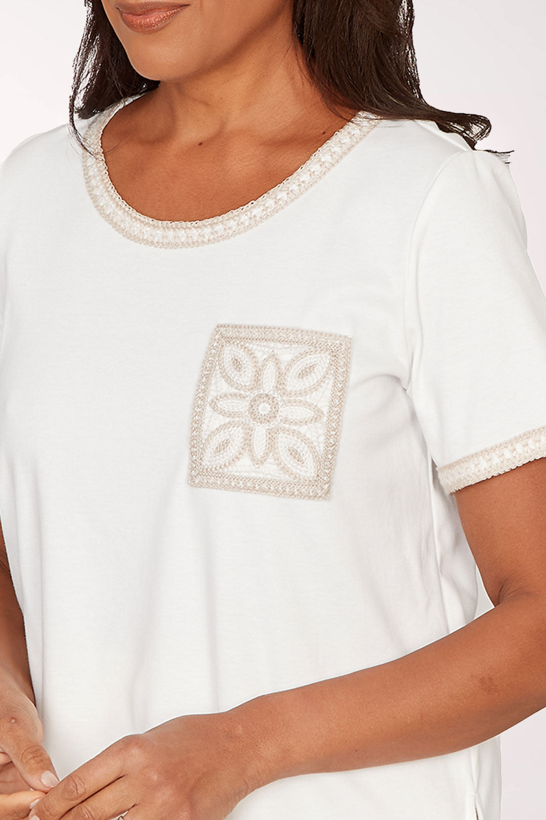 Woman wearing a white t-shirt with a square design on a plain background
