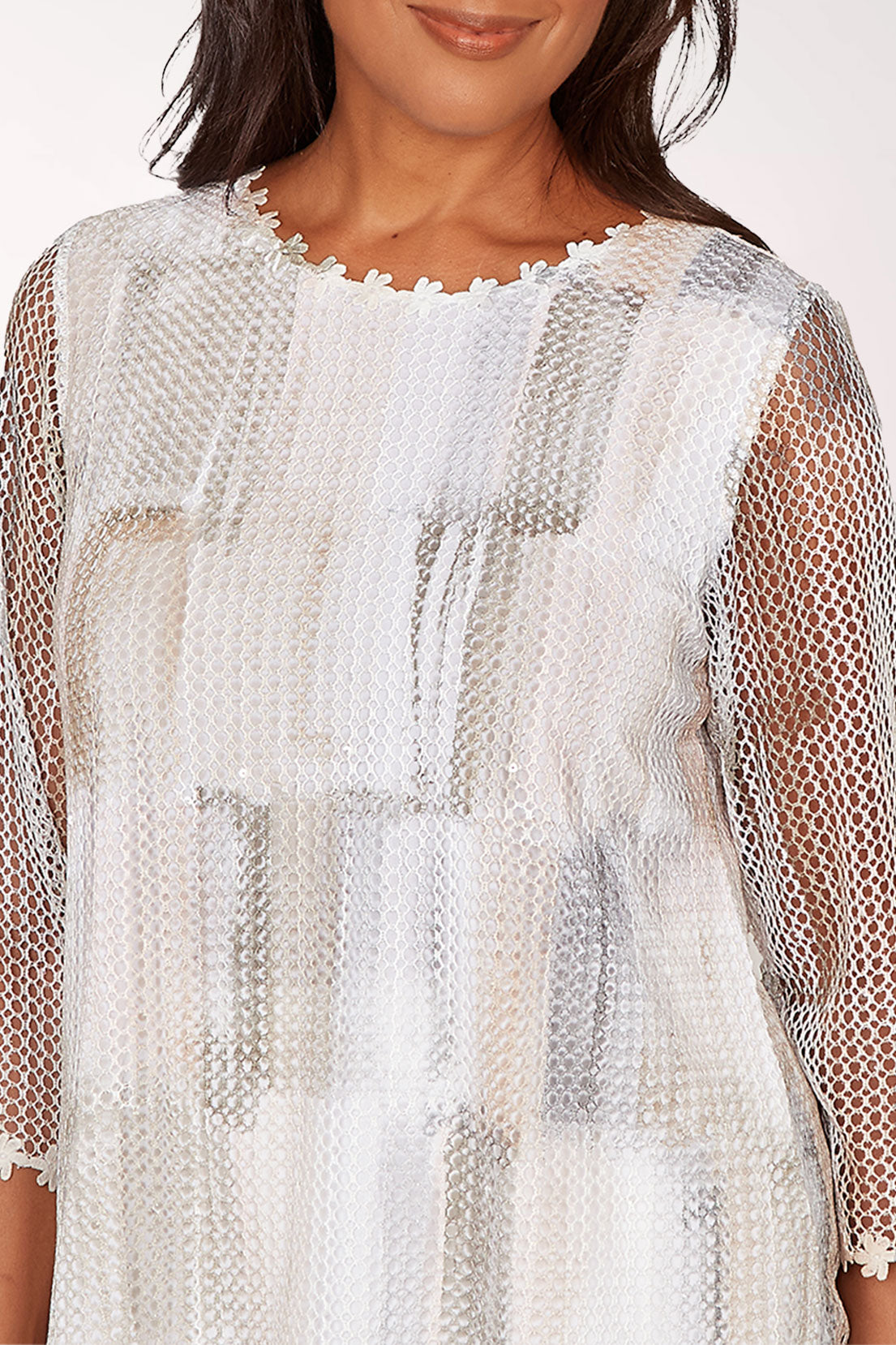 Woman wearing a sheer white top with a subtle pattern on a white background
