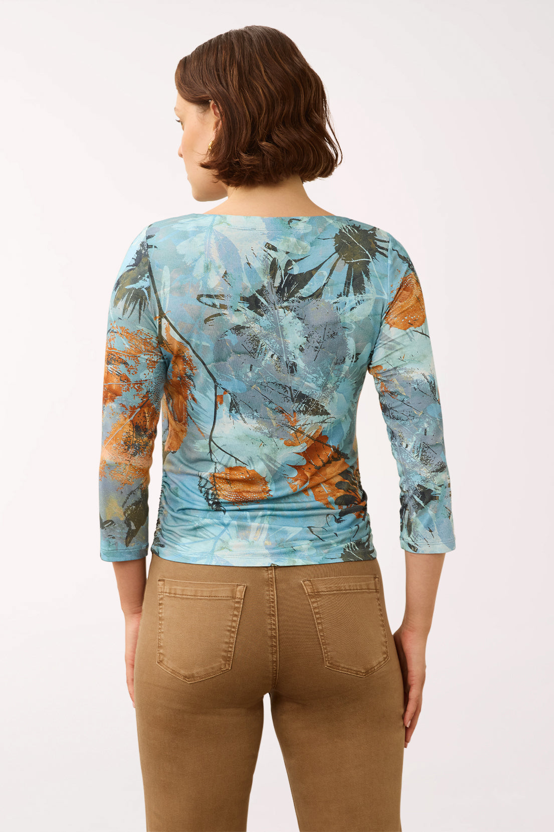 Woman wearing a 3/4 sleeve blue and multicolored top with a sunflower print