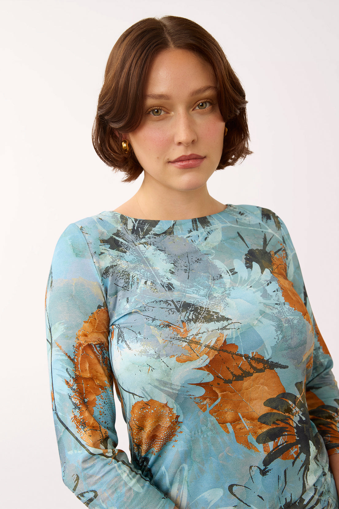 Woman wearing a 3/4 sleeve blue and multicolored top with a sunflower print