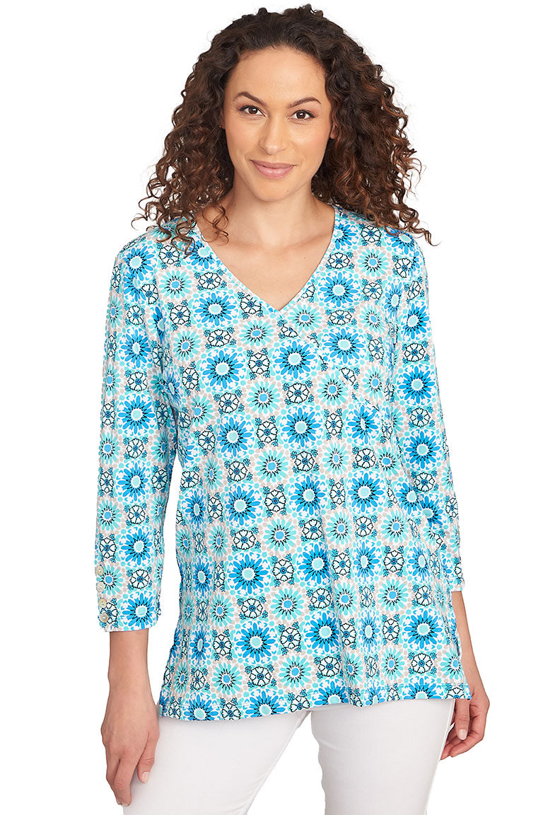 A front shot of a model wearing a blue and white medallion surplice top with 3/4 sleeves and a V-neck.