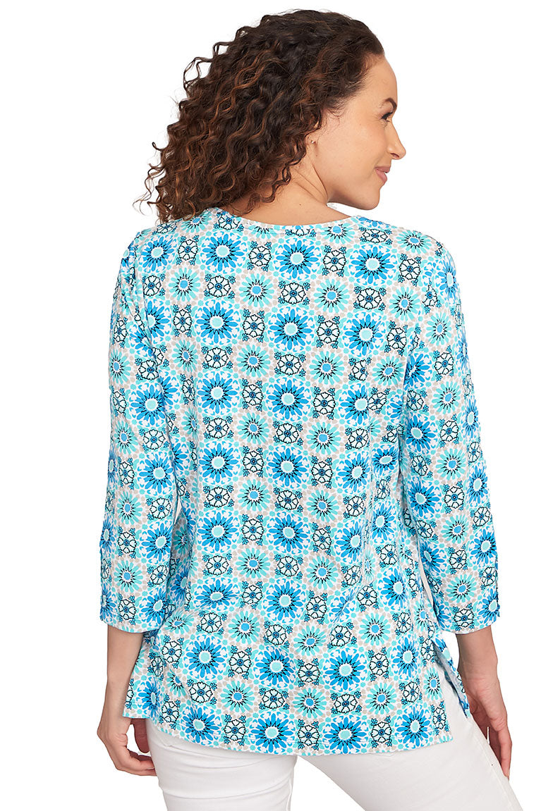 A back shot of a model wearing a blue and white medallion surplice top with 3/4 sleeves and a V-neck.