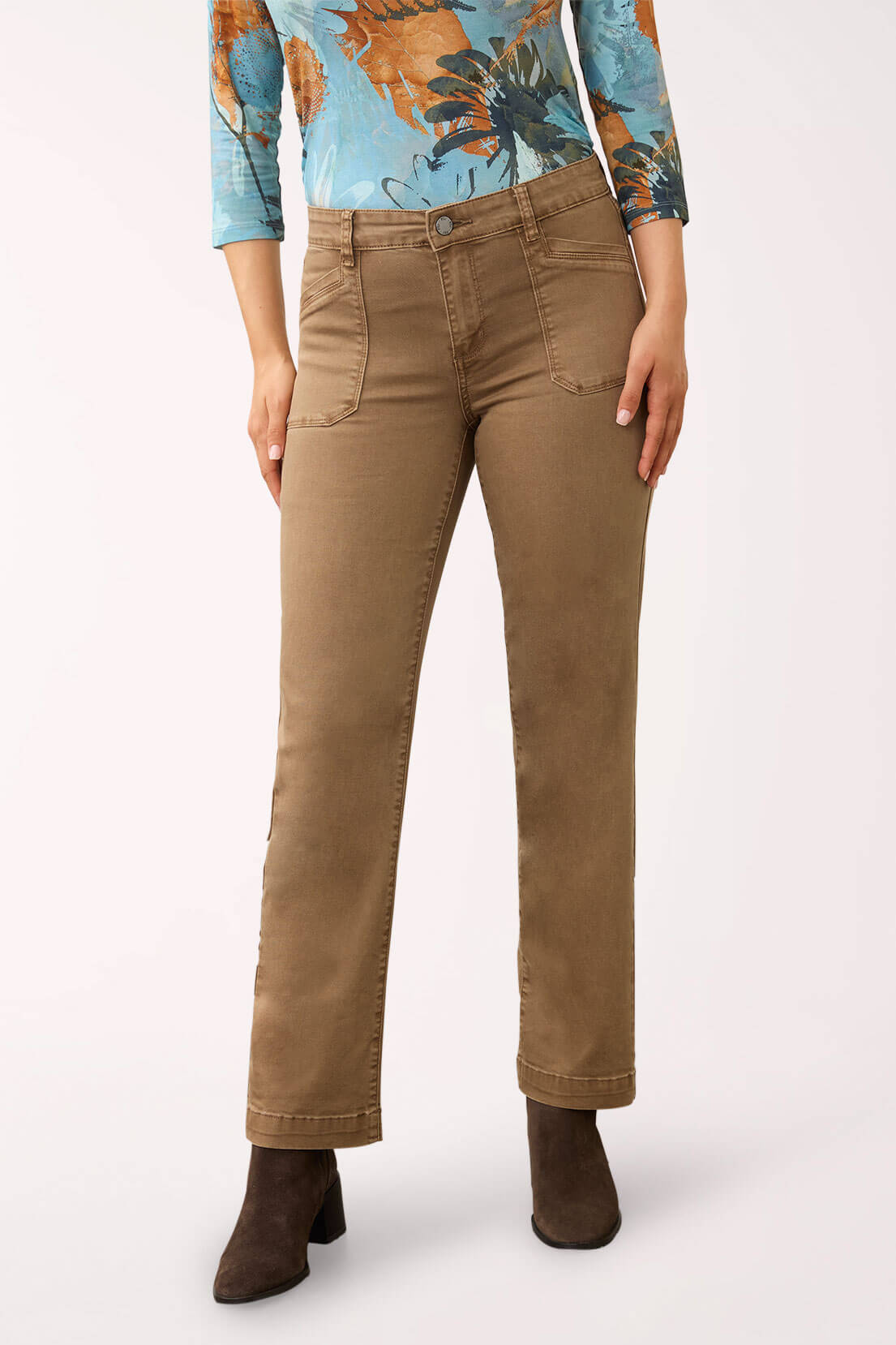 A model is shown from the waist down wearing a pair of straight-leg brown pants, a blue floral long-sleeve top, and dark brown ankle boots, set against a plain light background.