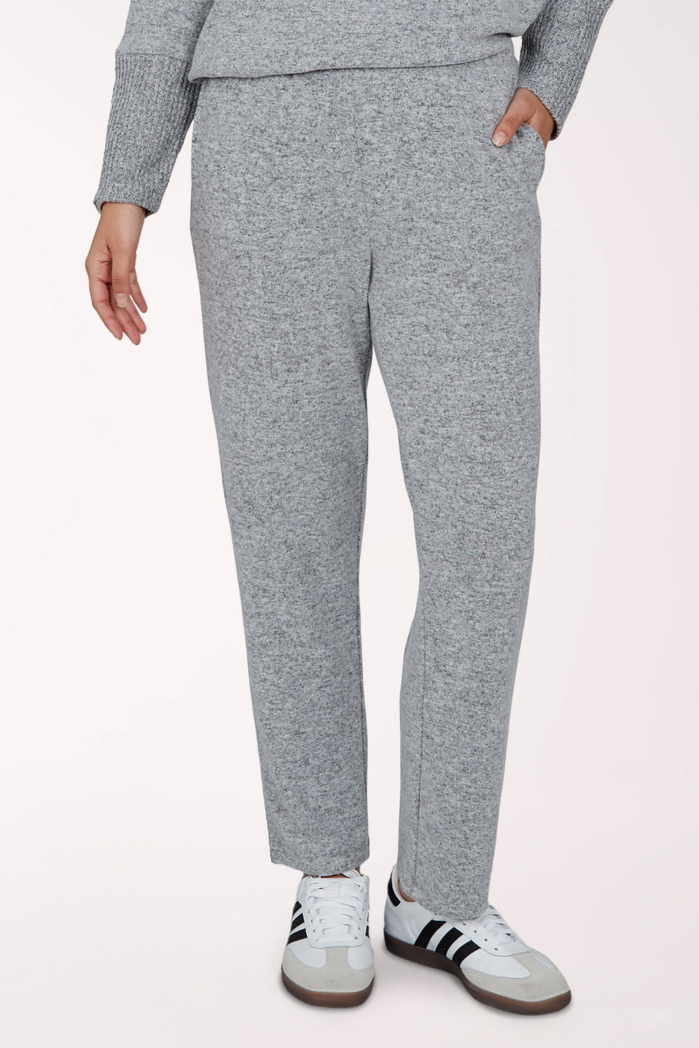A person wearing heathered grey lounge pants with a matching long-sleeve top and white sneakers, shown from the waist down against a plain light background.