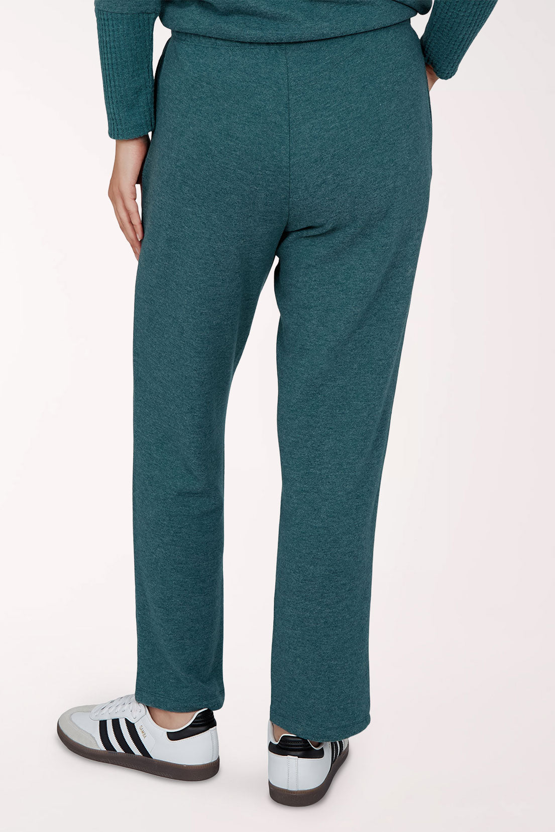 A person wearing heathered teal lounge pants with a matching long-sleeve top and white sneakers, shown from the waist down against a plain light background.