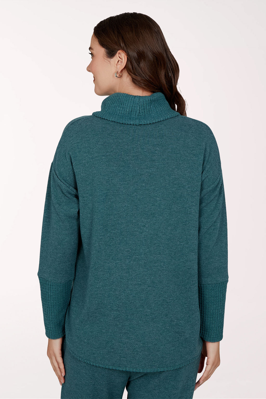 A woman shown from the back wearing a teal green ribbed mock neck sweater and matching knit pants against a plain light background.