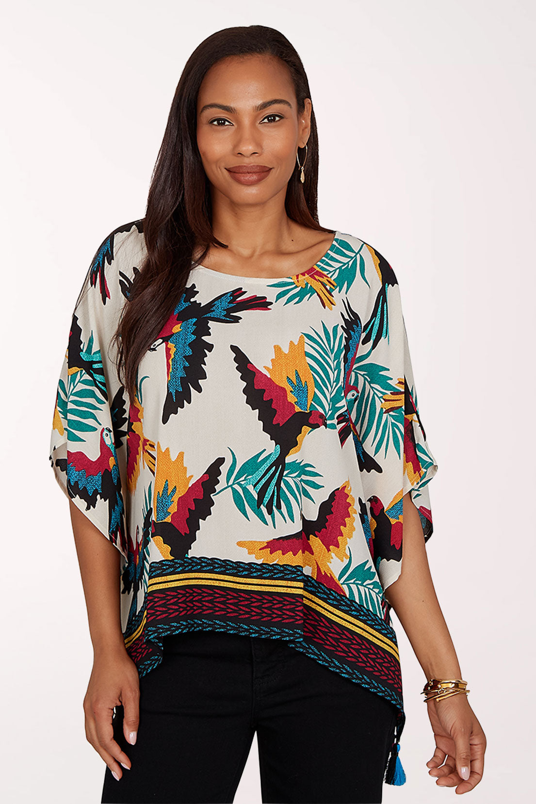 Woman wearing a colorful parrot and leaf patterned top on a white background
