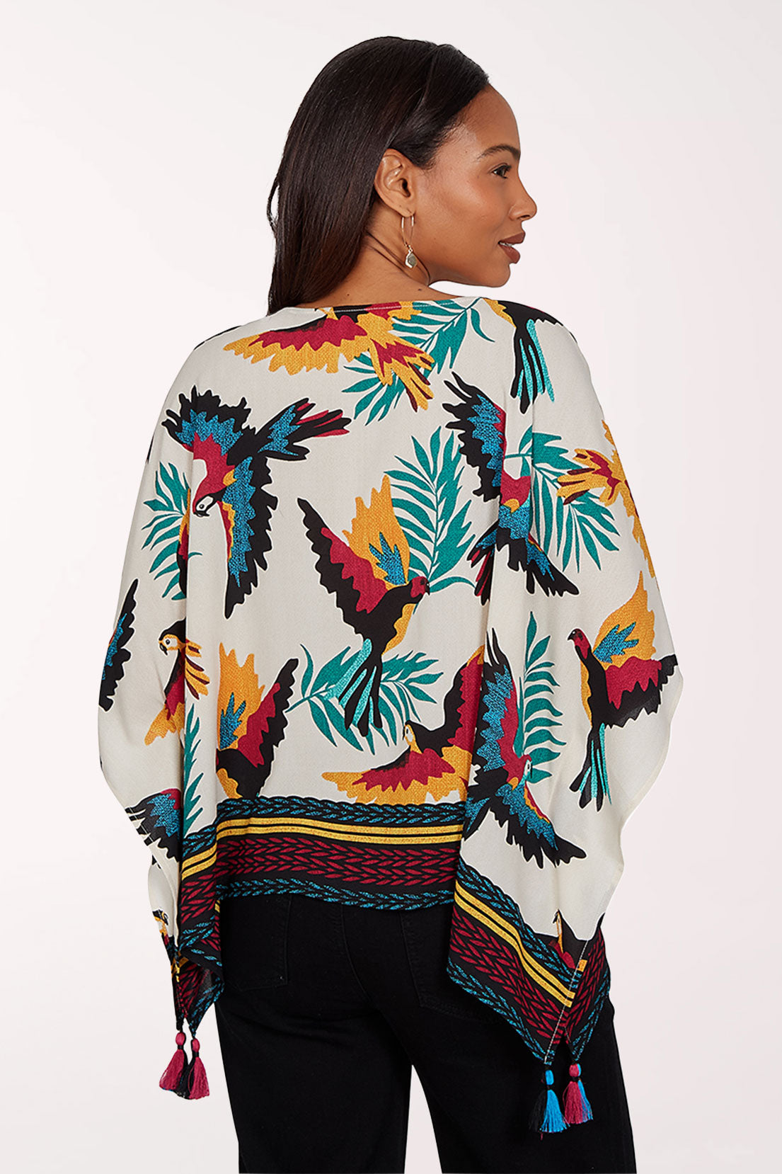 Woman wearing a colorful parrot and leaf patterned top on a white background
