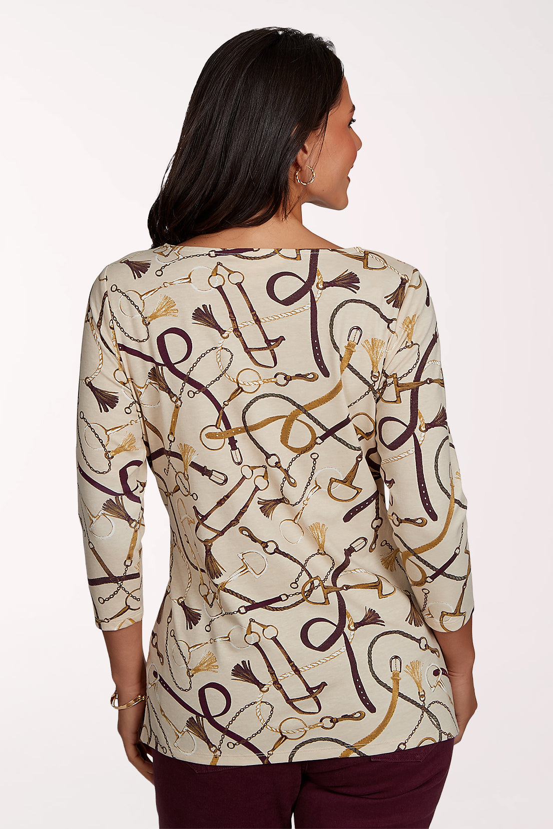 Woman wearing a 3/4 sleeve beige top with an equestrian pattern