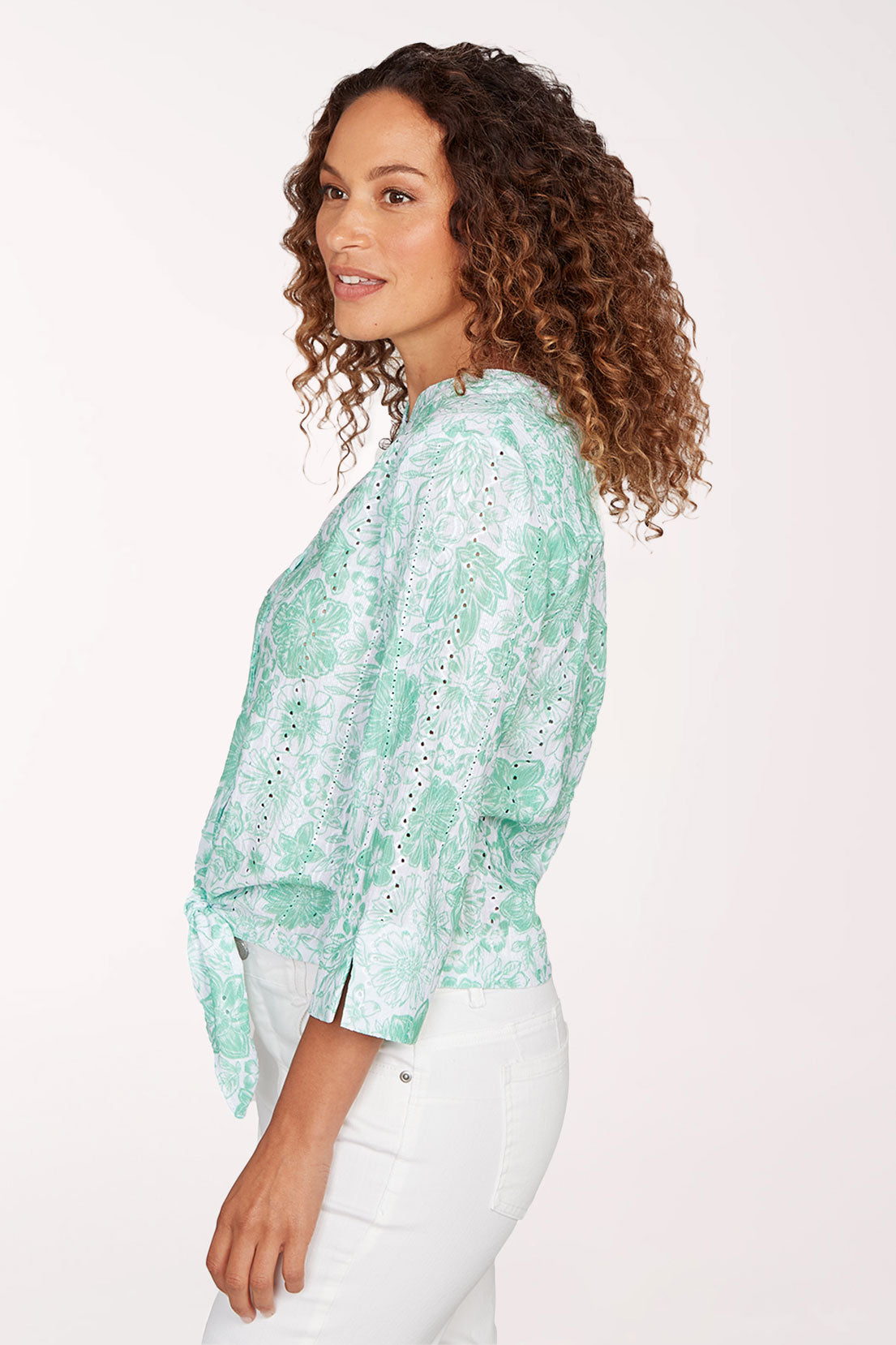 Woman wearing a light green floral blouse with a white background
