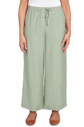 A front shot of a model wearing bay leaf green wide-leg pants with tan flats.