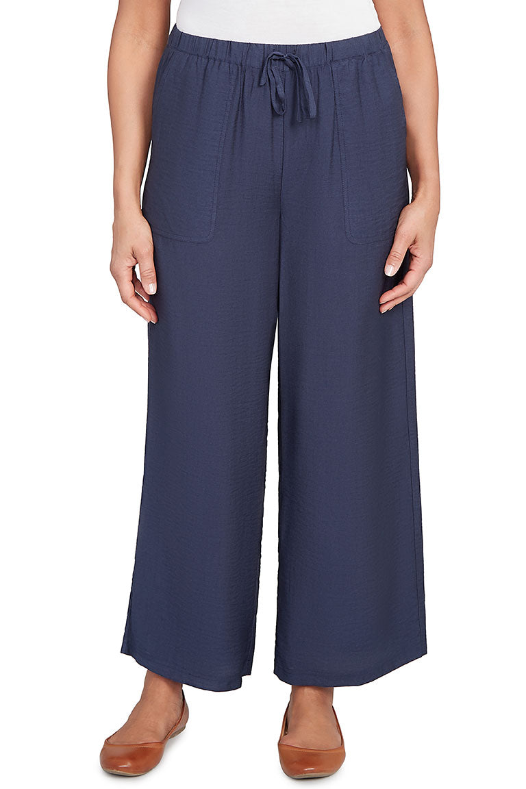 A front shot of a model wearing navy wide-leg pants with tan flats.