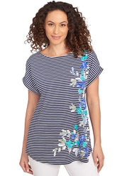 A front shot of a model wearing a navy and white striped tunic with floral designs on a white background