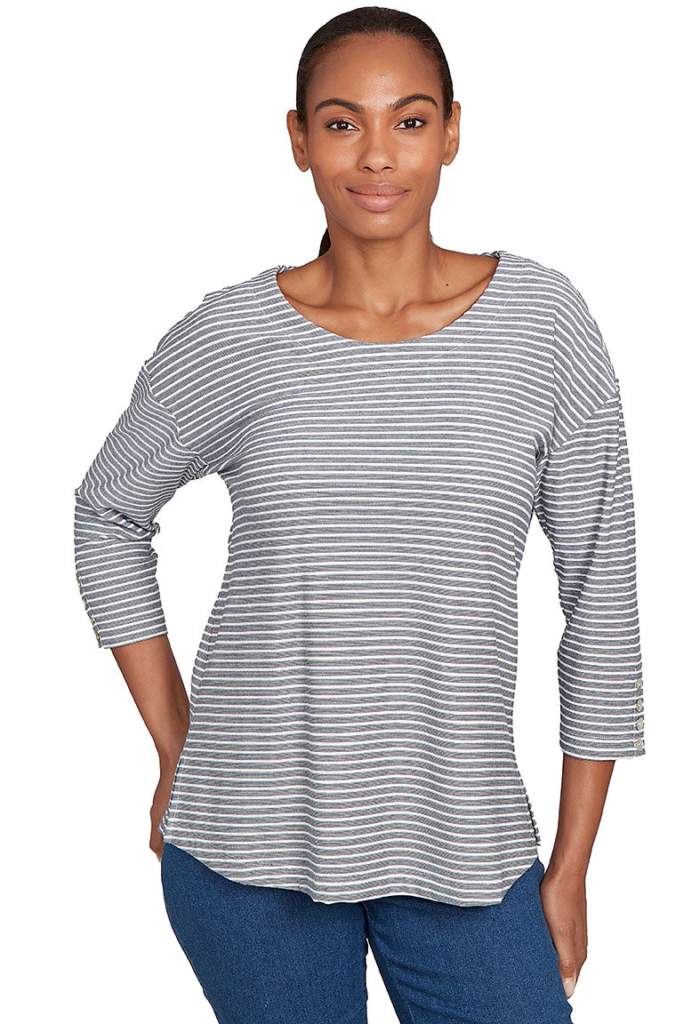 A front shot of a model wearing a gray and white striped long-sleeve top with blue jeans on a white background