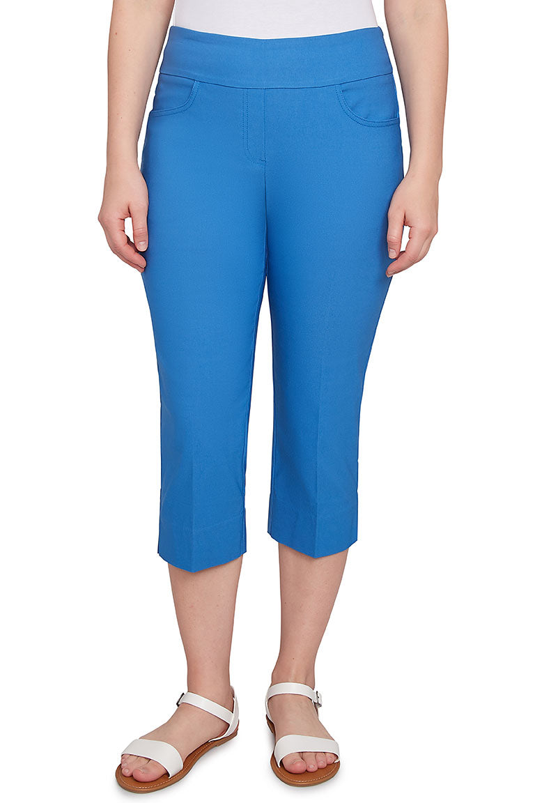 A front shot of a model wearing a azure-colored pull-on silky capri pant with an elasticized waistband, dual front and back pockets, and a straight hemline with side slits.
