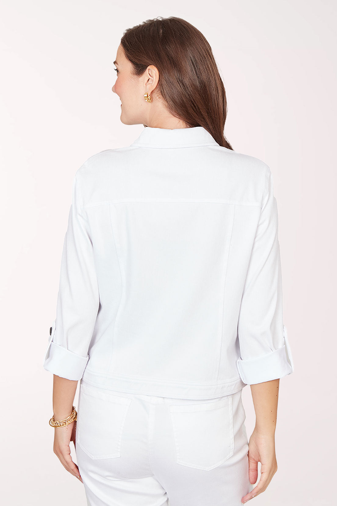 Woman wearing a white jacket with black buttons on a light pink background