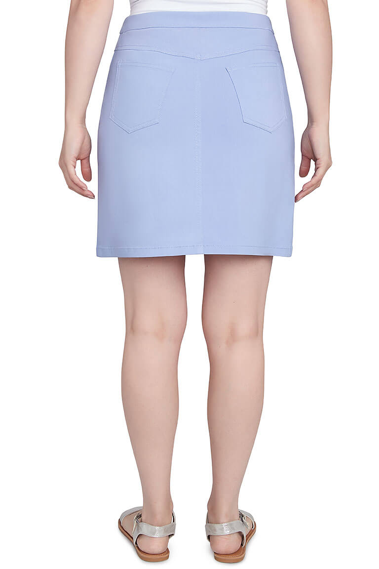 A back shot of a model wearing a blue skort with a straight hemline and classic 5-pocket styling. The skort is knee-length and the person is also wearing silver sandals.