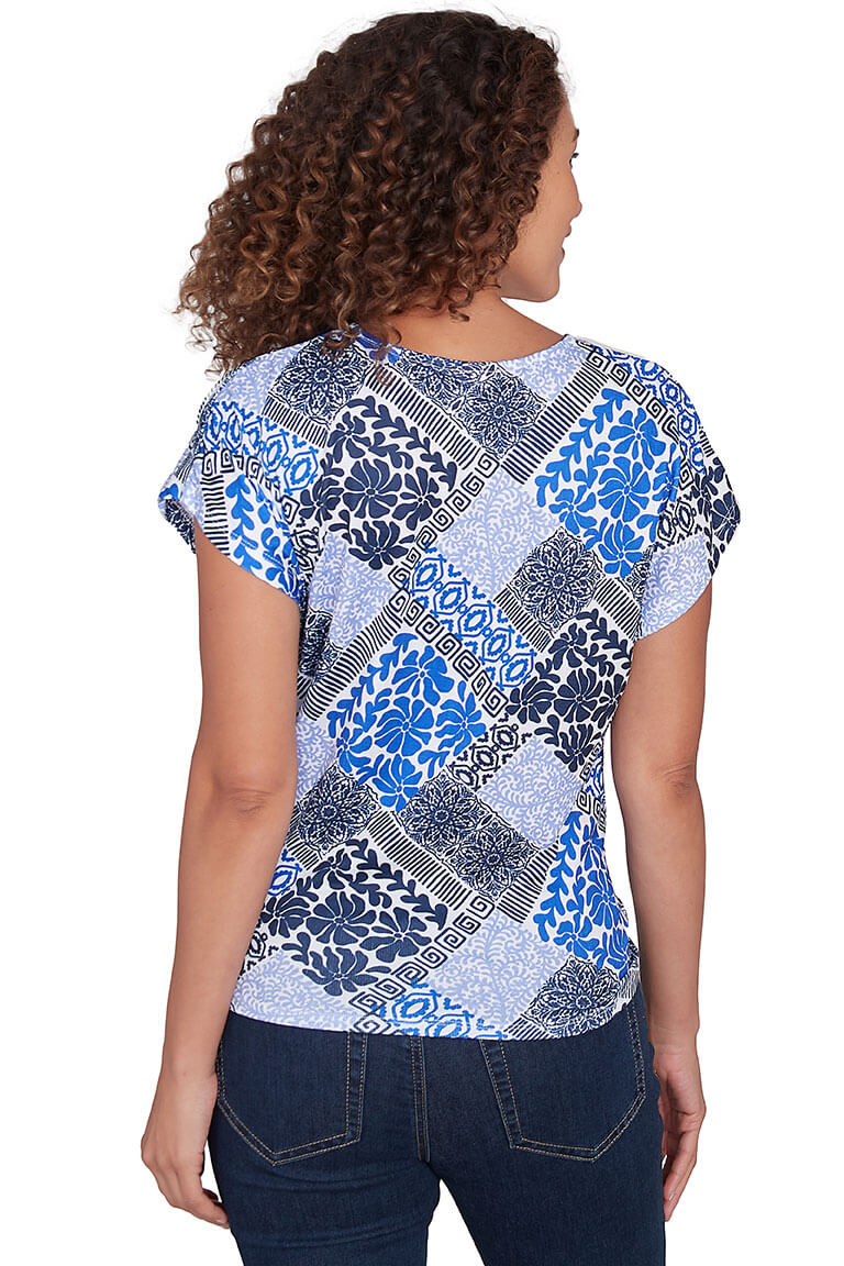 A back shot of a model wearing a blue and multicolor crinkle textured v-neck knit top with dolman cap sleeves and a tie-front hemline.