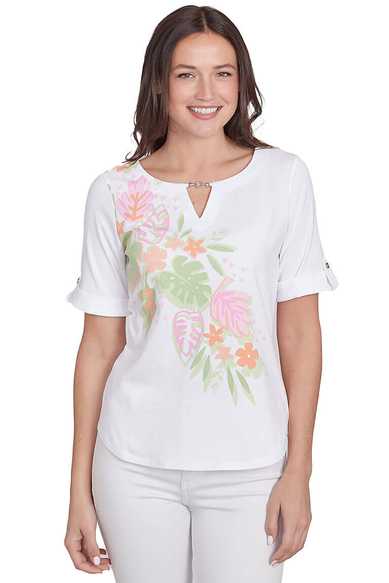 A front shot of a model wearing a white top with tropical leaf prints and short sleeves. The top features a notched neck and metallic closure on the neckline.