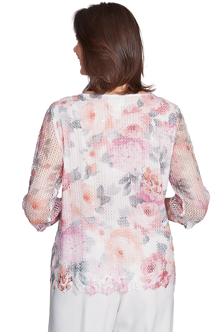 A back shot of a floral mesh top with sequined detailing and 3/4 length sleeves. The top features a scoop neckline with floral trim, sheer sleeves with floral trim on cuffs, and a floral trim on the hemline with side slits.
