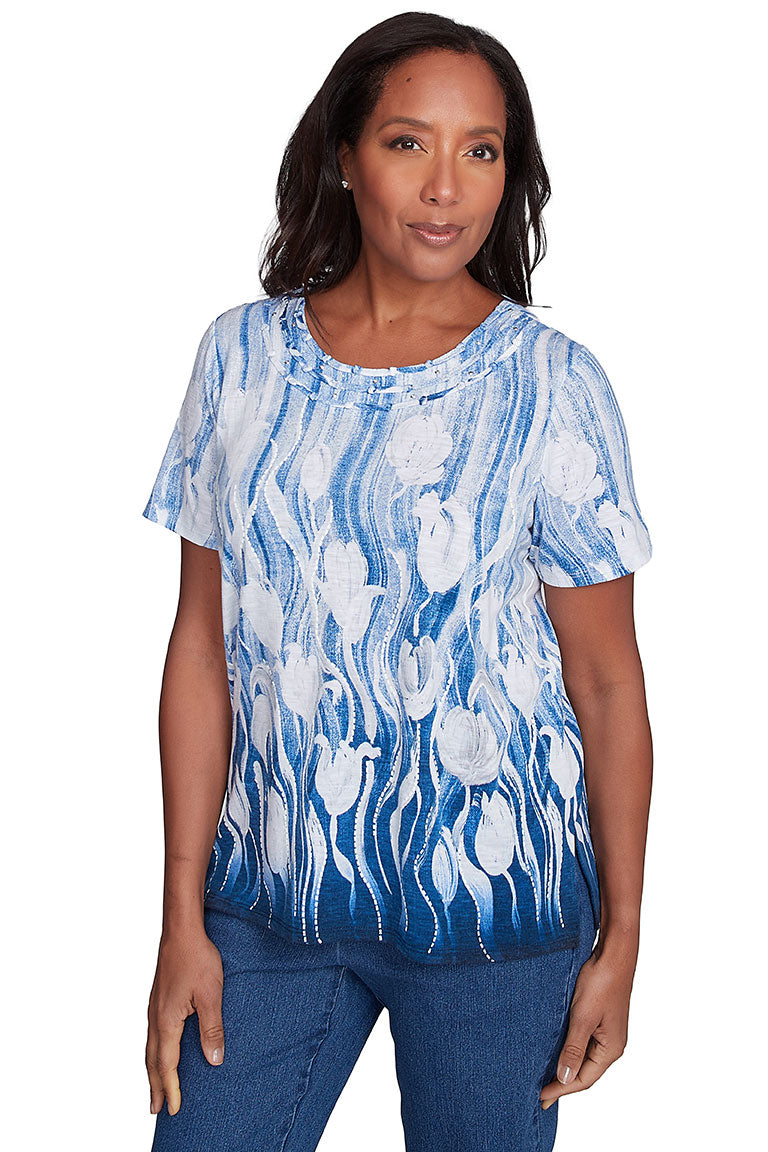 A woman wearing a blue and white floral knotted neck top with short sleeves and a round neckline.