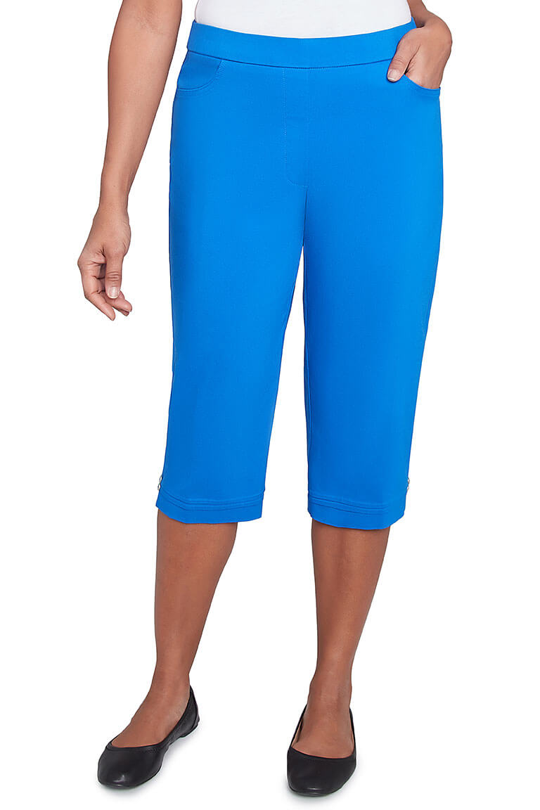 A pair of cobalt blue pleated hem capri pants with a stretch waistband, dual front pockets, and button detail on the hemline.