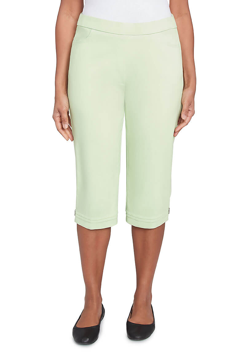 A pair of parrot green pleated hem capri pants with a stretch waistband, dual front pockets, and button detail on the hemline.