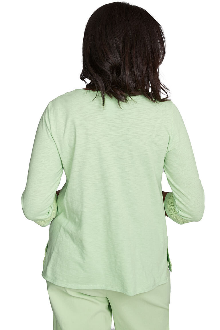 A back shot of a woman wearing a green Parrot Cay lace trim top with a notched v-neckline and 3/4 sleeves, paired with matching green pants.