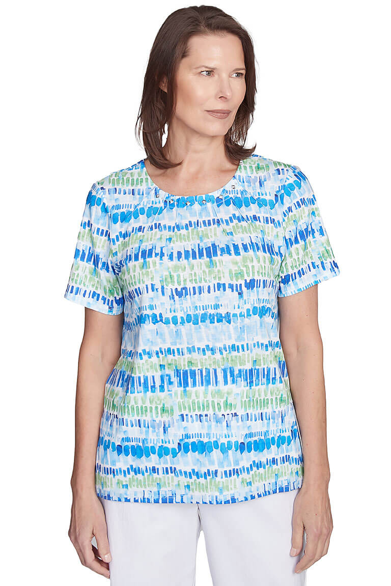 A woman wearing a short-sleeved blue and green pleated neck tee with rhinestone embellishment at the neckline.