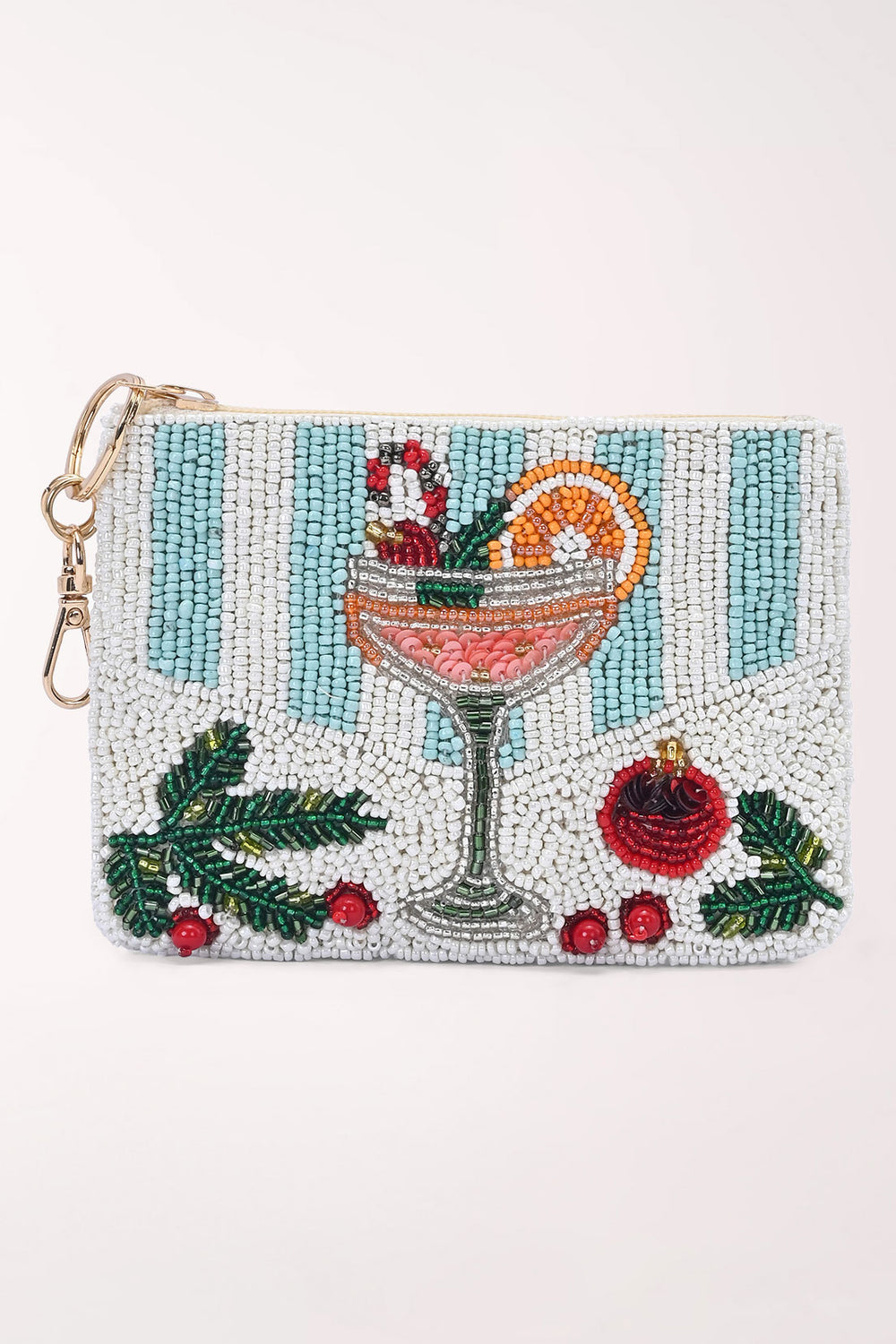 Angled front view of a white beaded coin pouch with pale blue stripes, a pink mimosa cocktail with an orange slice and candy cane, green holly and a red ornament, with a gold zipper pull, key ring and dog hook.