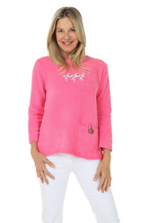 Woman wearing a pink sweater with a flamingo logo on a white background