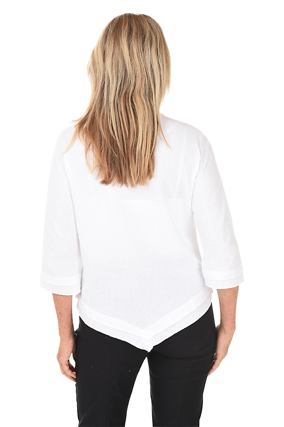 A woman wearing a white scoop neck blouse with 3/4 dolman sleeves and a pointed handkerchief hemline. Back shot.