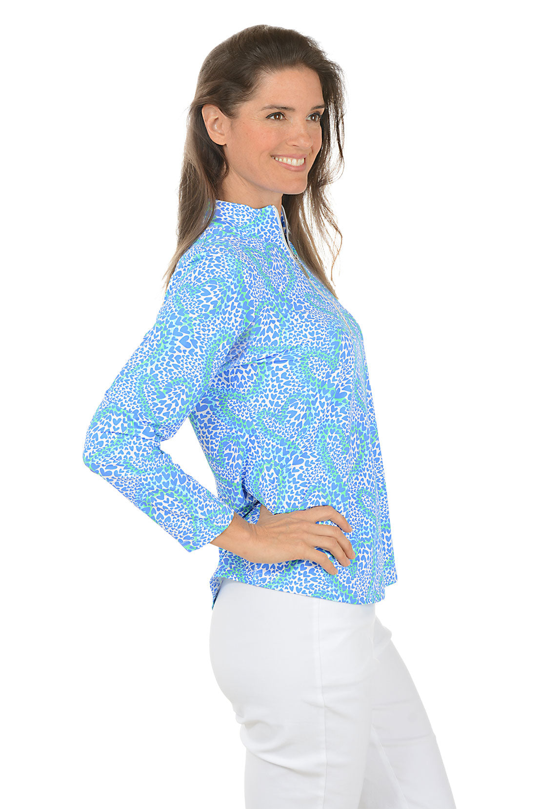 Woman wearing a blue patterned long-sleeve top on a white background. Side shot.