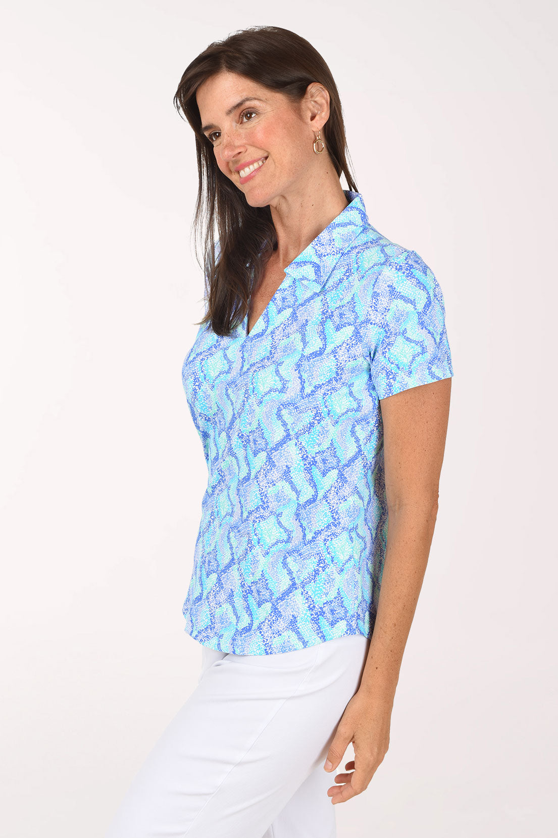 Side view of the Blue Snakeskin Polo Top showing the short sleeve and curved hem over white pants.