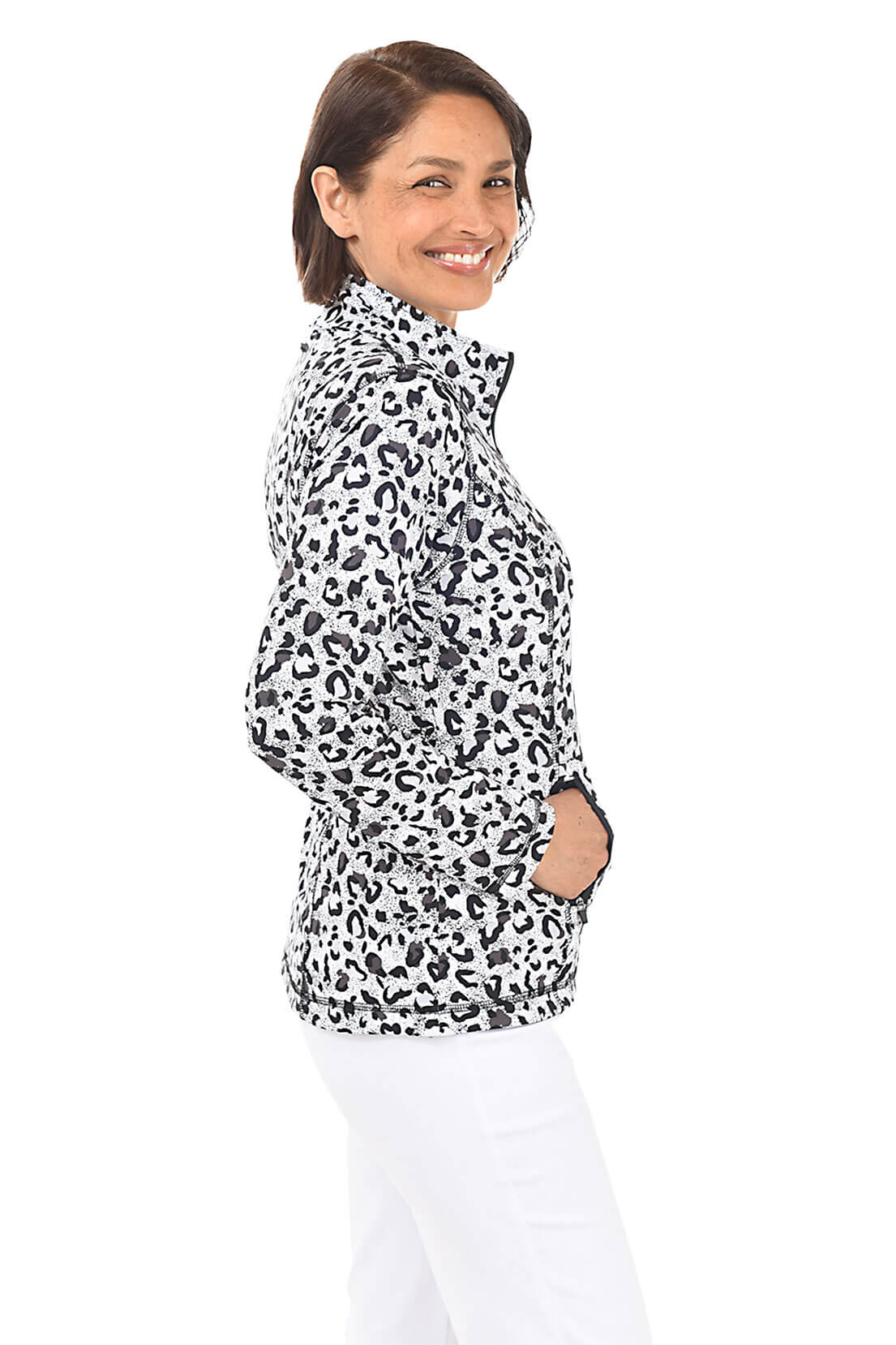 A woman wearing a black and white leopard-spotted zip front jacket and white pants in front of a white background. Side shot.