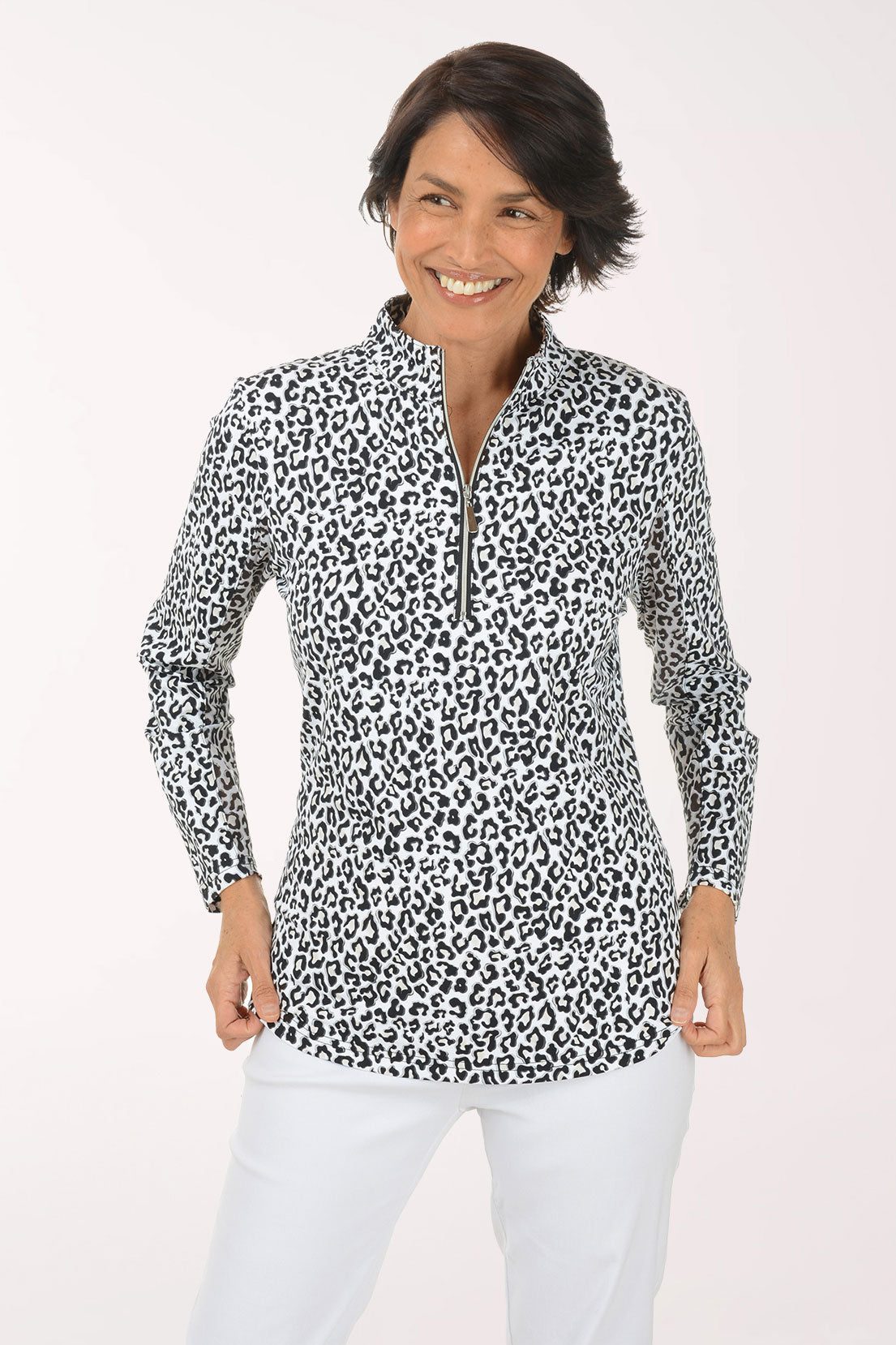 Woman wearing a leopard print blouse and white pants on a light background