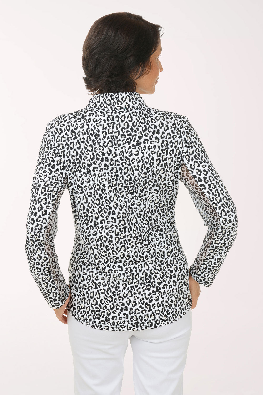 Woman wearing a leopard print blouse and white pants on a light background
