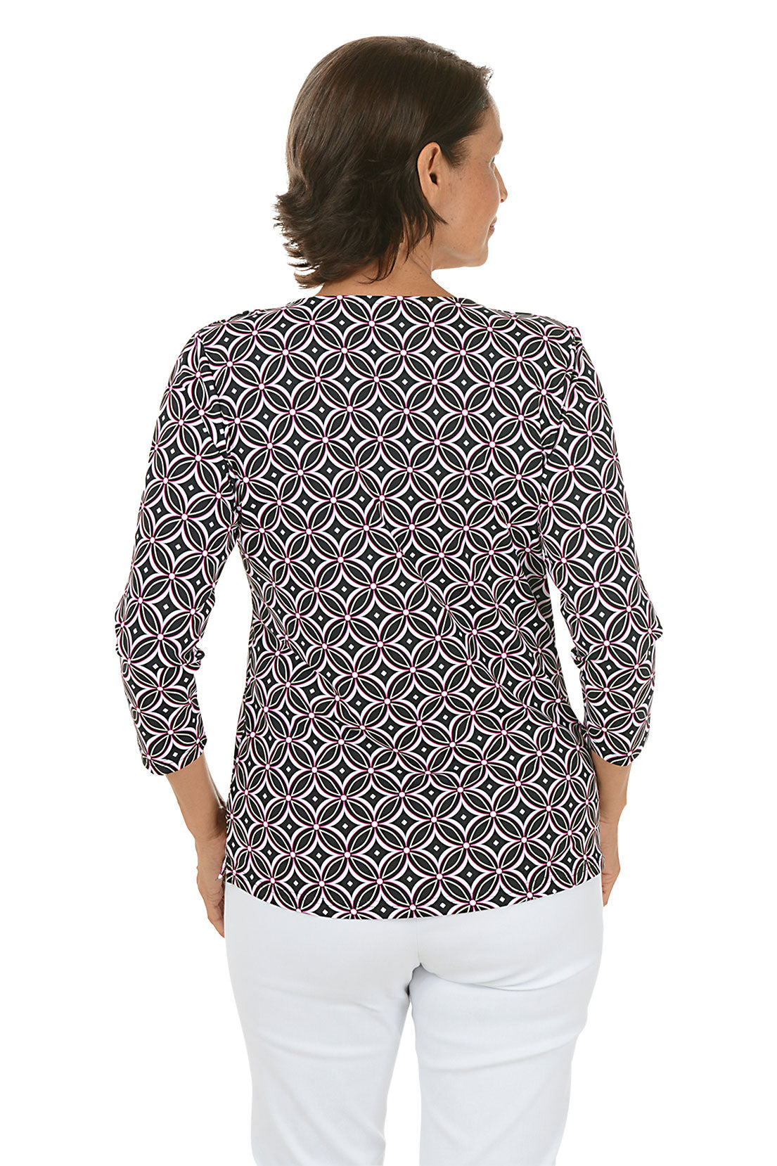 Woman wearing a black and white patterned top and white pants on a white background. Back shot.