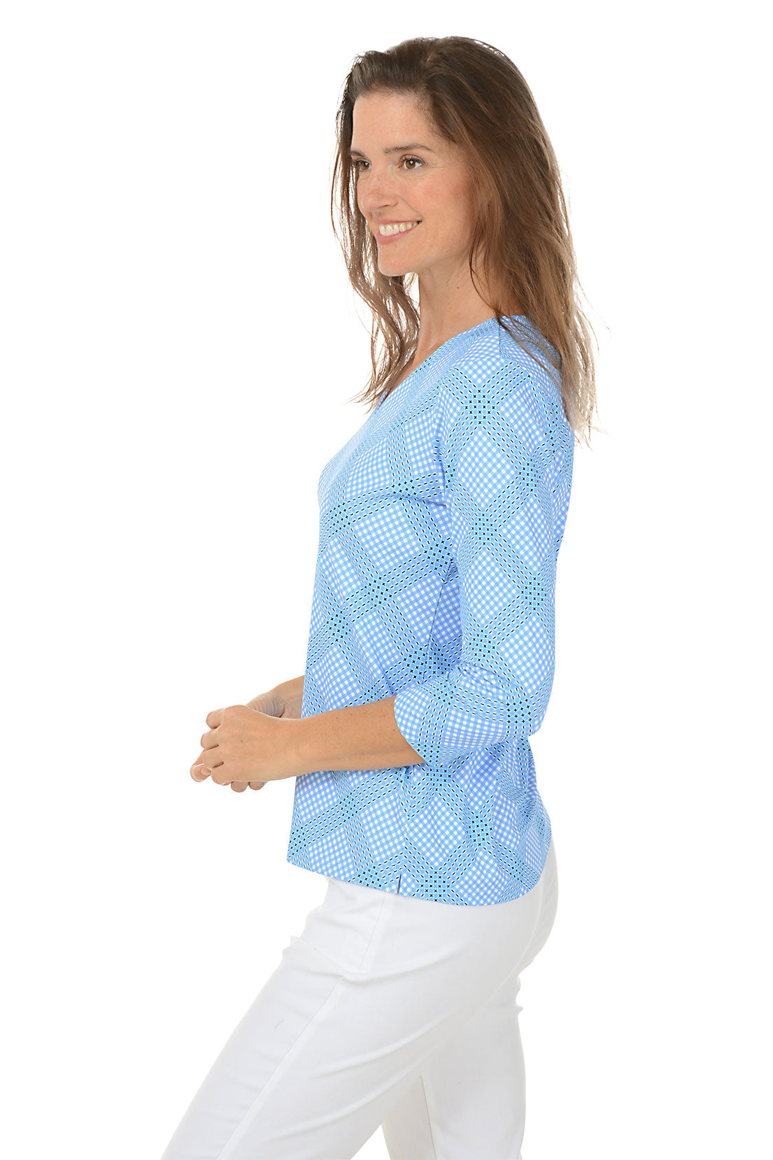 A woman wearing a blue checkered V-neck top with 3/4 sleeves, paired with white pants. Side shot.